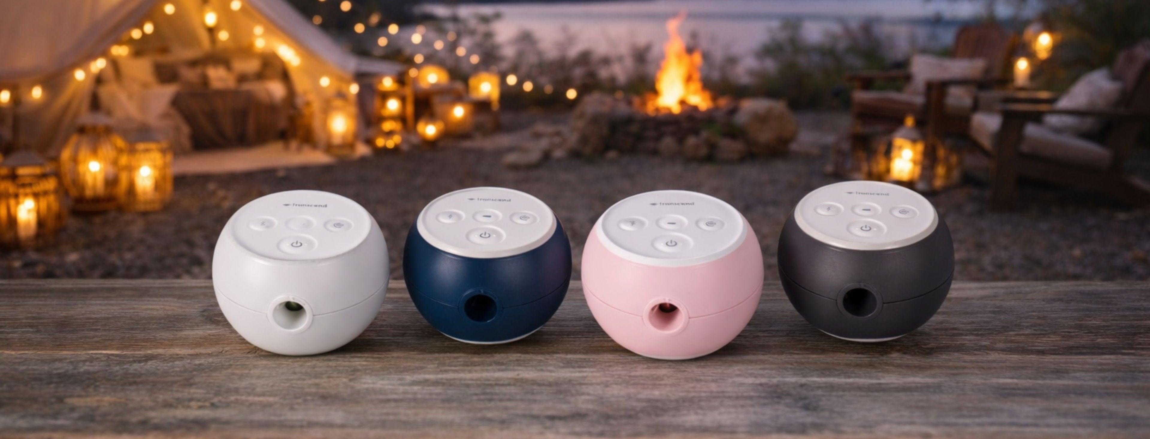 Four different coloured Transcend Micro 510 on a wooden surface with a warm, outdoor setting in the background with lights and a firepit.
