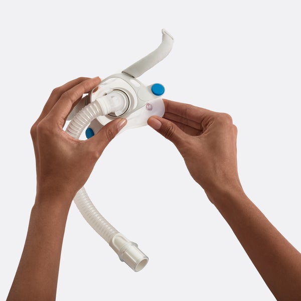 Person holding the Resmed AirFit F40 frame system attached to a CPAP hose on a light gray background