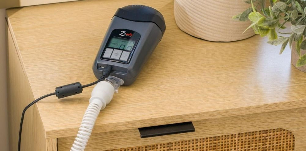 Breas Z2 CPAP device on wooden nightstand connected to tube and power