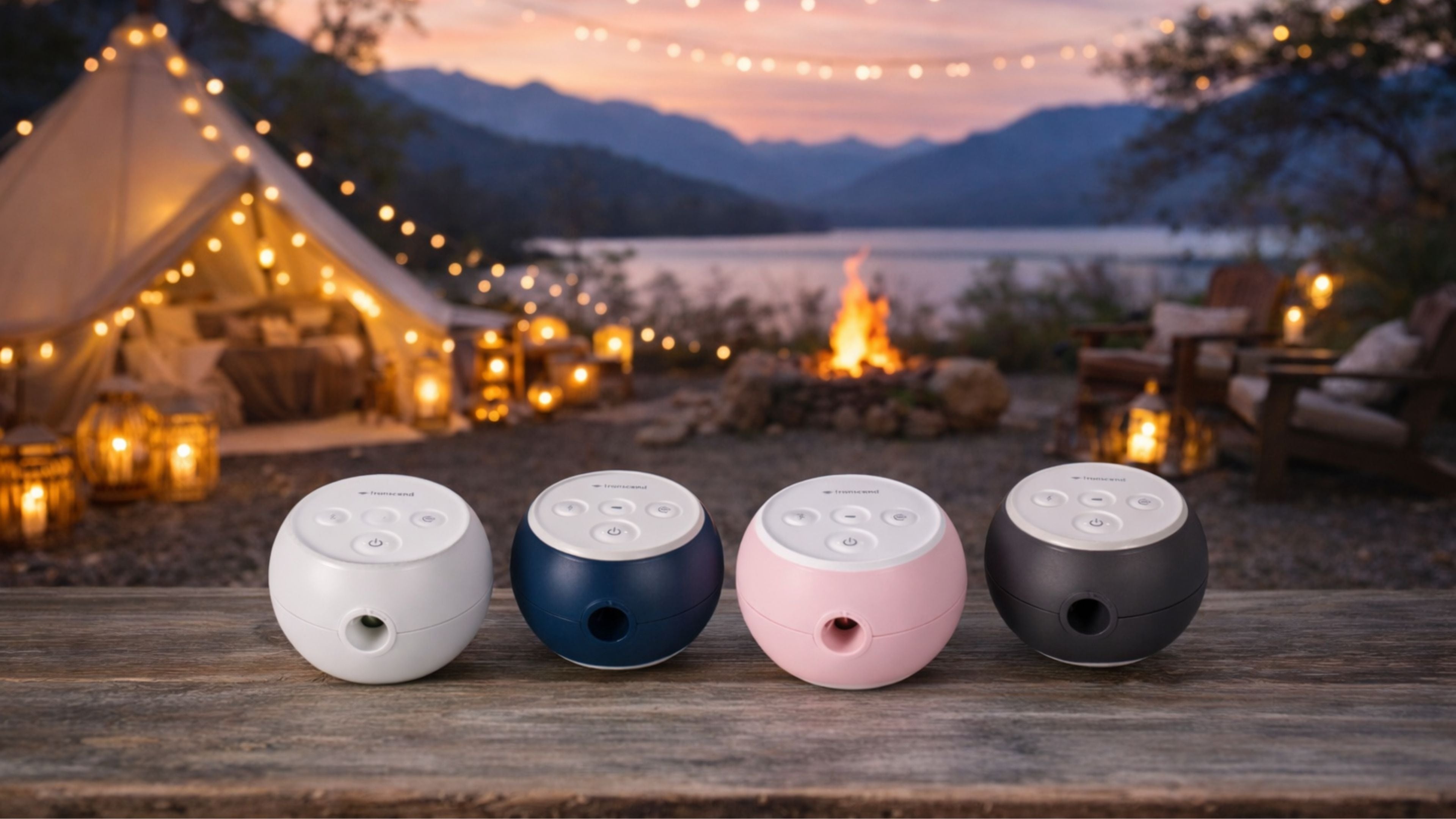 Four different colour Transcend Micro 510s on a wooden surface with a scenic background of tents, lights, candles, a fire and a lake.