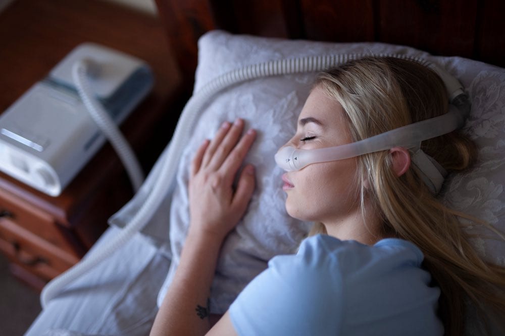 Person using a DreamStation CPAP machine in bed with a DreamWear mask on