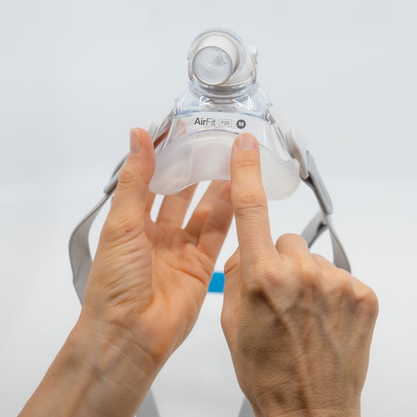 Person holding a ResMed AirFit P10 mask against a white background