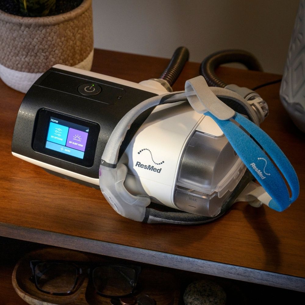 ResMed AirSense 11 CPAP machine and AirTouch N30i mask on a wooden nightstand with a blurred background