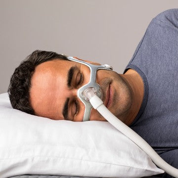 Man using a nasal CPAP mask while side sleeping on a pillow
