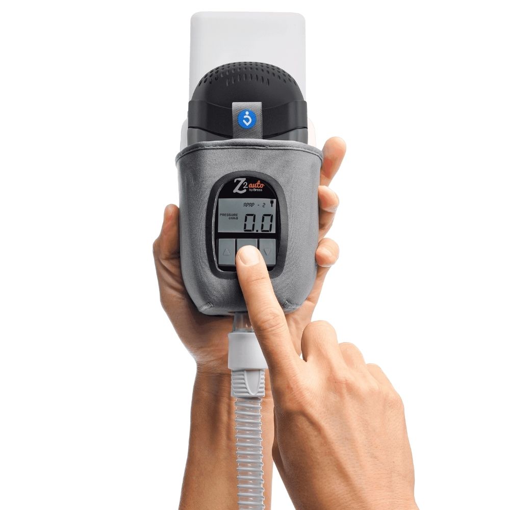 Hand holding the Z2 Travel CPAP machine with a finger pressing one of the buttons