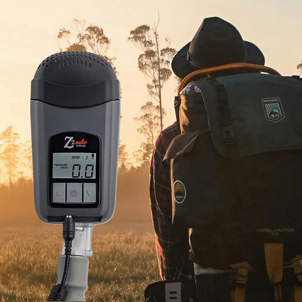 Person with a backpack with the Z2 CPAP device shown in a field during sunset