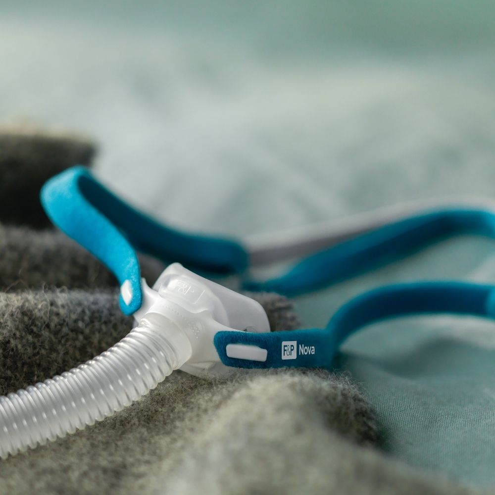 F&P Nova Micro Nasal Pillow Mask on a bed