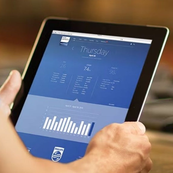 Person holding a tablet displaying the data from the Philips DreamMapper app with a blurred background