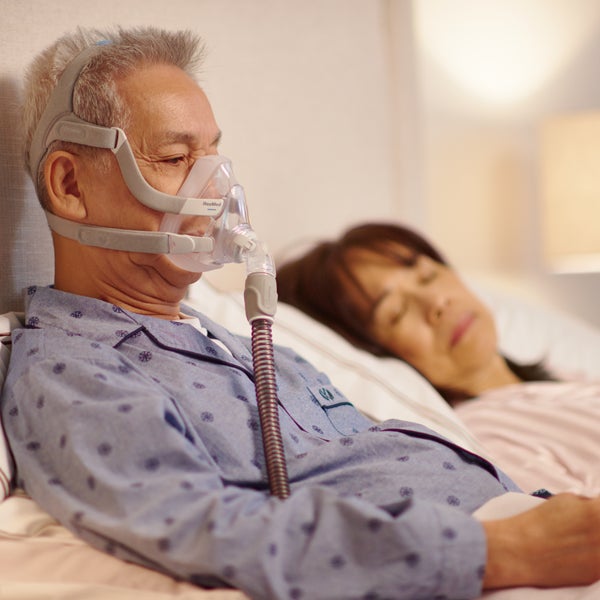 Man using the ResMed AirFit F20 full face CPAP mask in bed