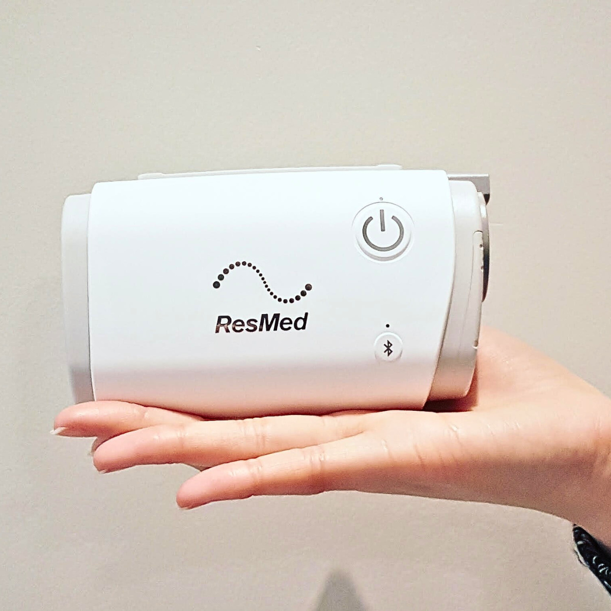 Hand holding a ResMed AirMini device