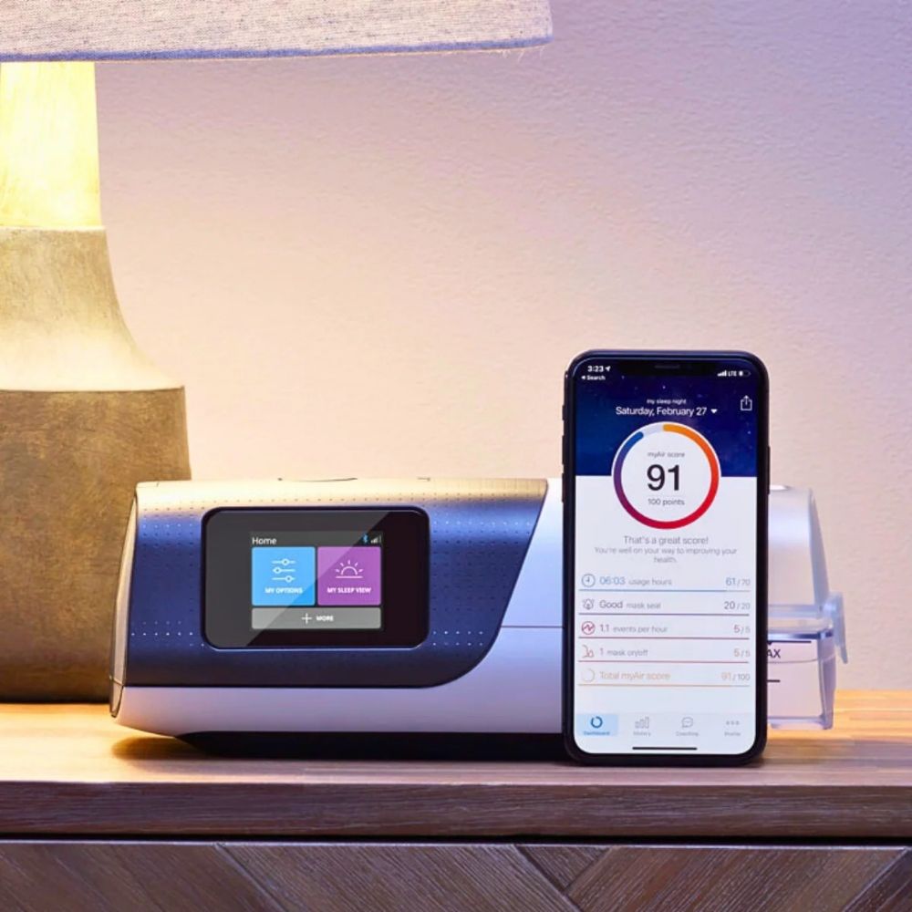 AirSense 11 on nightstand with a smartphone displaying ResMed's MyAir app