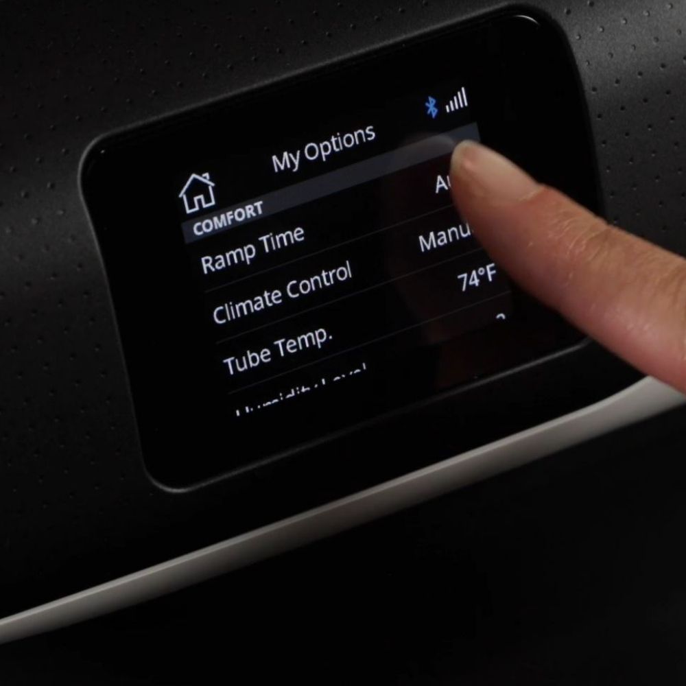 Person adjusting settings on the AirSense 11 CPAP machine's touchscreen display