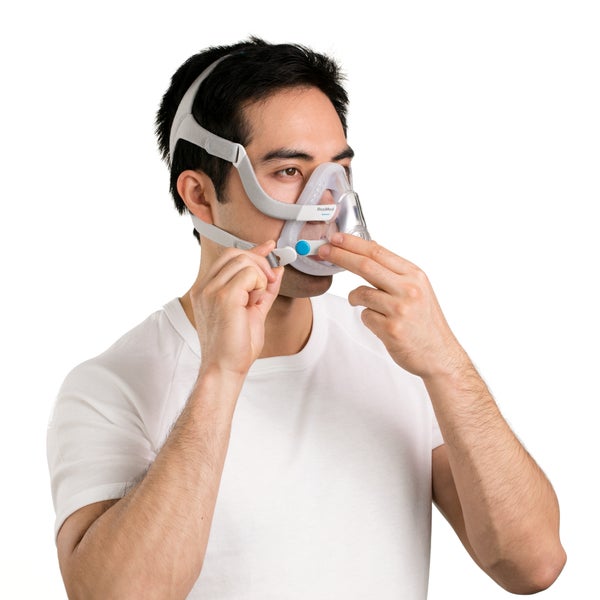 Man putting on the ResMed AirTouch F20 full face CPAP mask