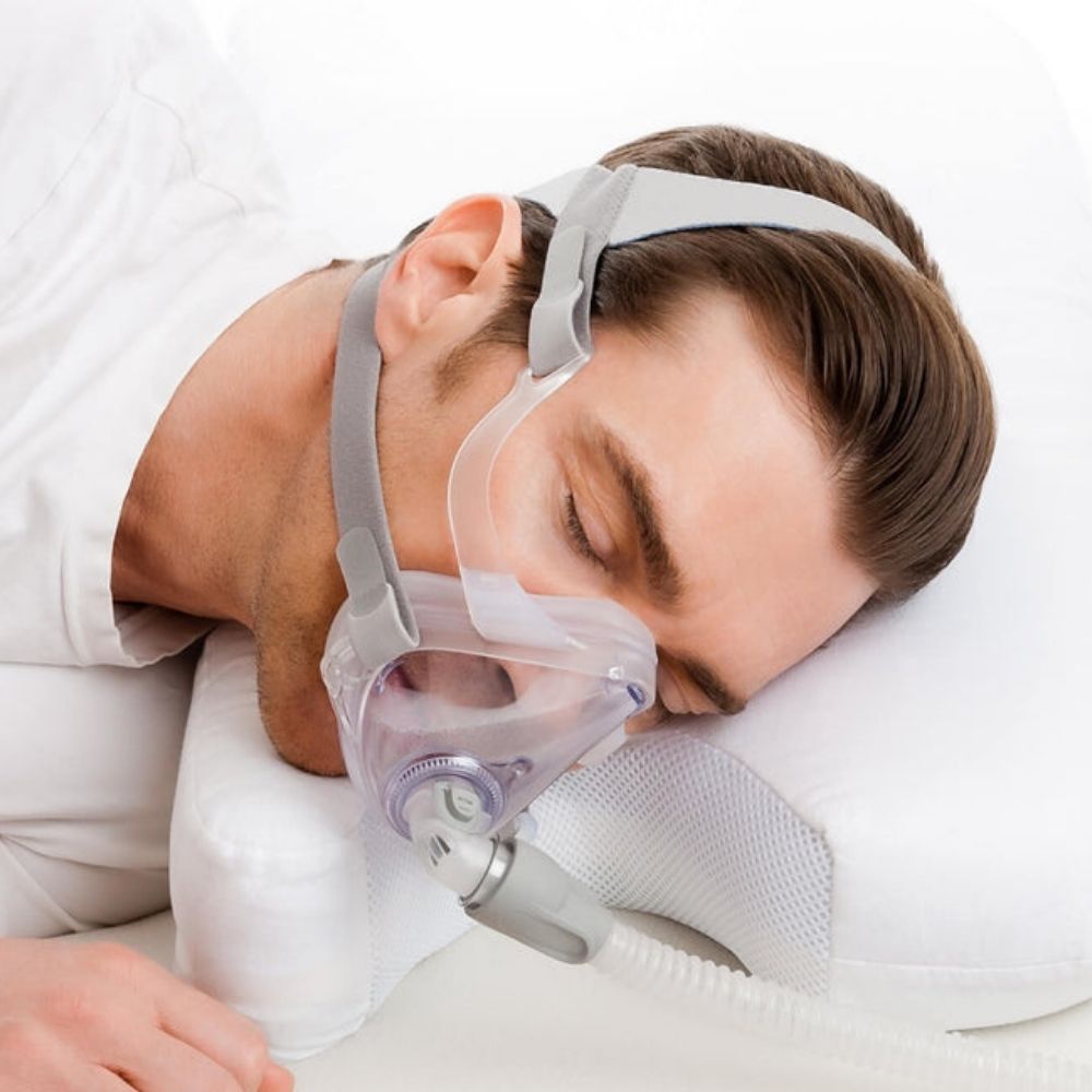 Person wearing a full face CPAP mask and using the Rest In Best Memory Foam CPAP Pillow with Herbal Infusion