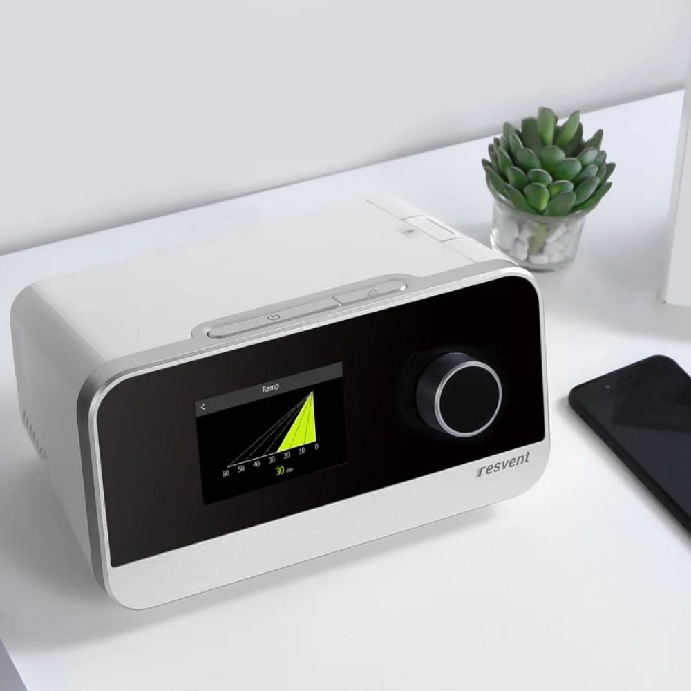 Resvent iBreeze Auto CPAP Machine on  desk beside a succulent and phone