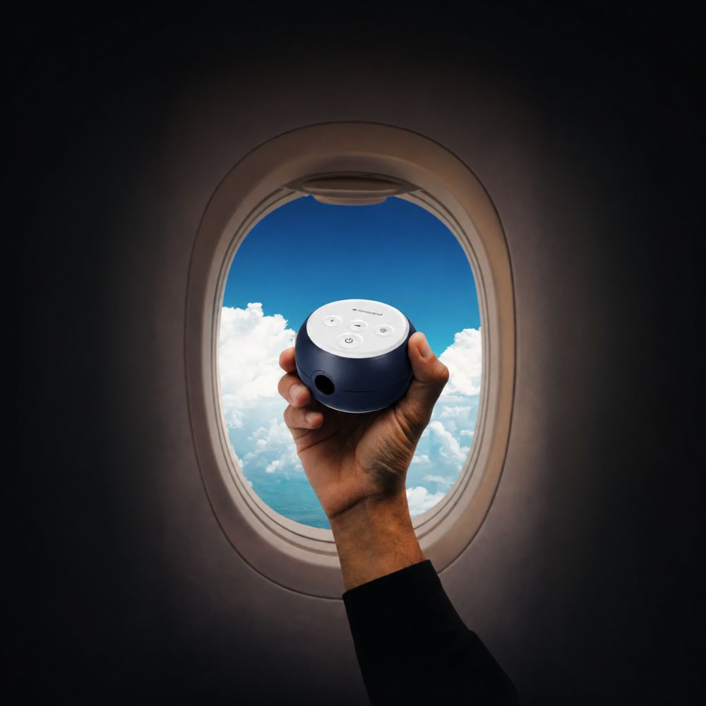 Transcend Micro 510 CPAP Machine in Midnight Blue held against an airplane window