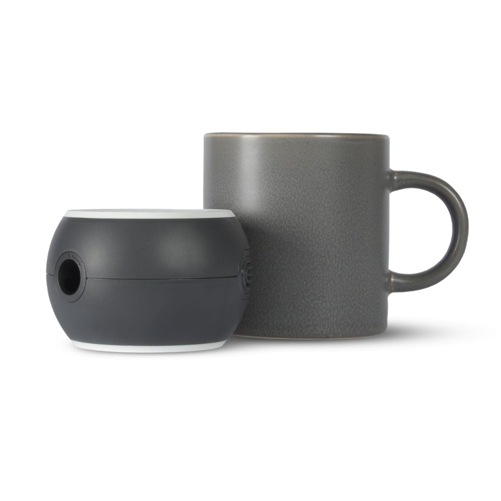 The Micro 510 CPAP machine in grey beside a standard size grey coffee mug that's taller than the machine