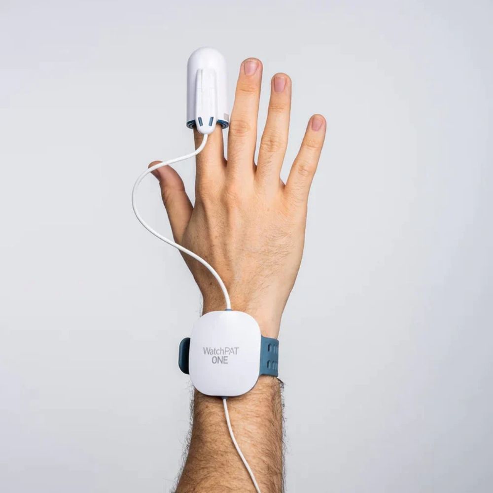 Hand wearing a white home sleep apnea testing device with 'WatchPAT ONE' branding on a gray background